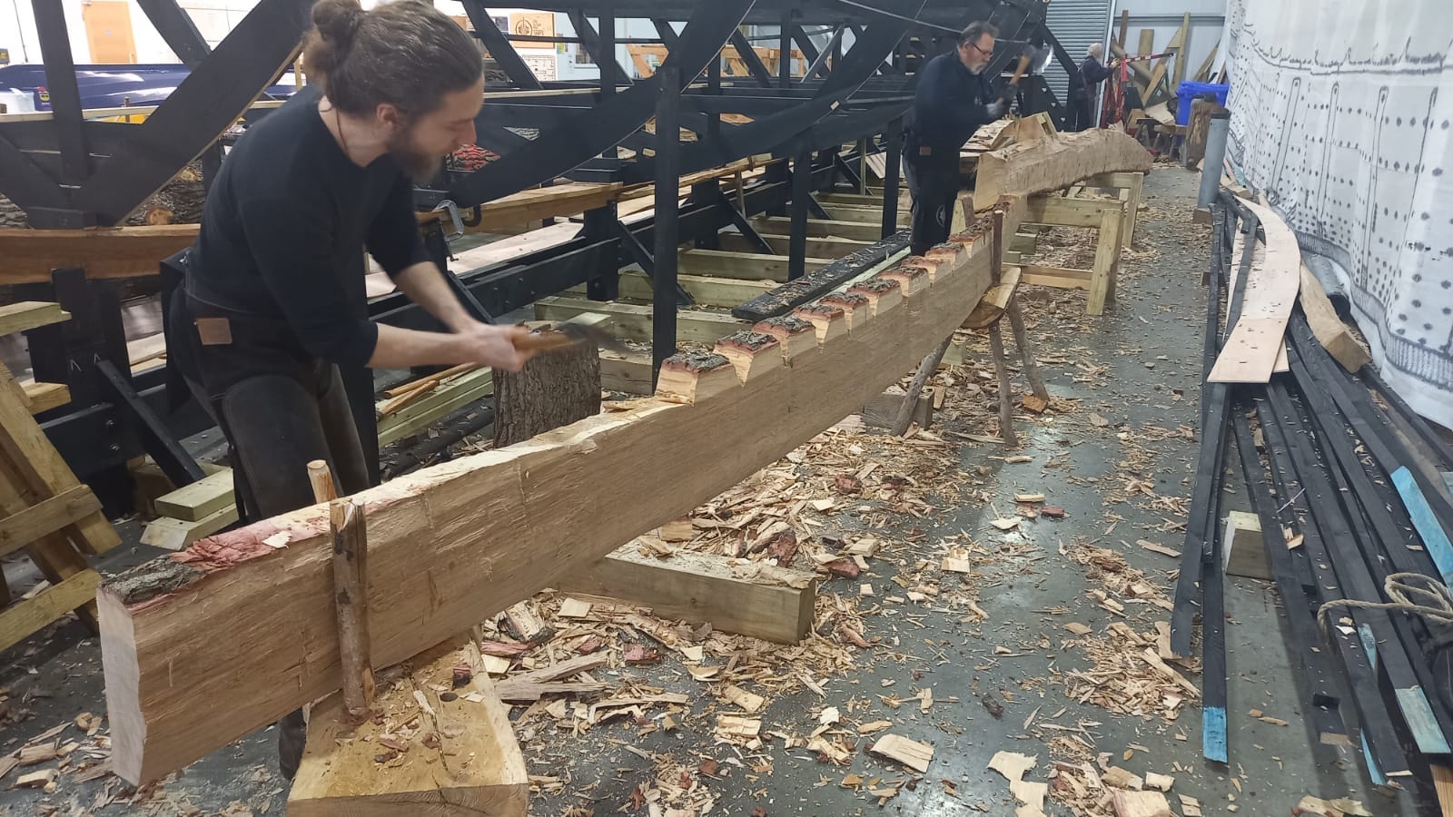 Alec Newland (foreground) and David MacDonald (background) hewing planks from cleaved logs